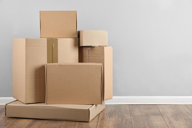 Photo of Pile of cardboard boxes near light blue wall indoors. Space for text