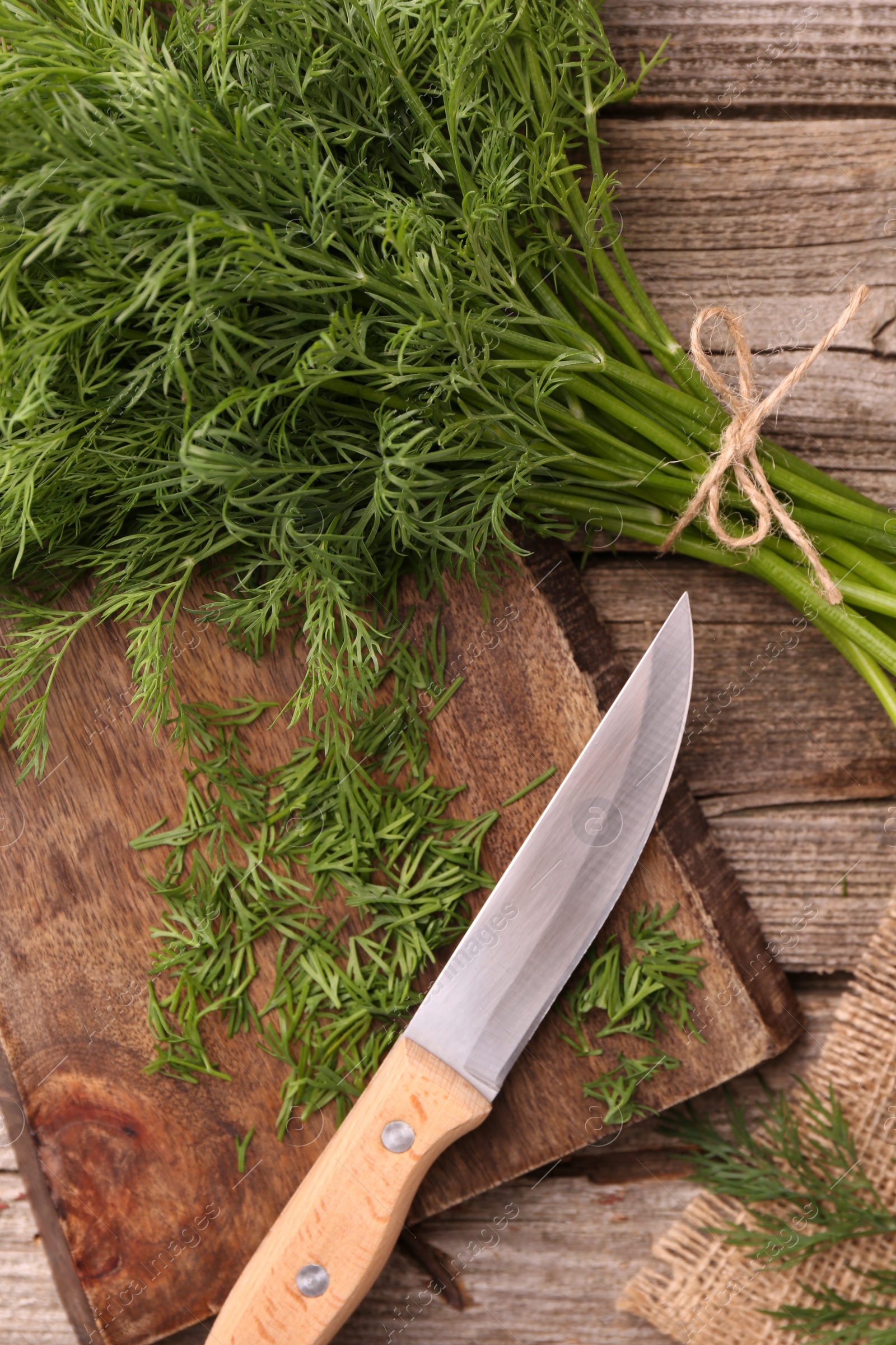 Photo of Fresh dill, cutting board and knife on wooden table, flat lay