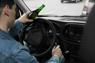 Photo of Man with bottle of beer driving car, closeup. Don't drink and drive concept