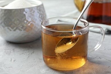 Tasty tea with sugar in cup on grey textured table, closeup