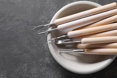 Photo of Set of different clay crafting tools on grey table, top view. Space for text