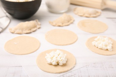 Photo of Process of making dumplings (varenyky) with cottage cheese. Raw dough and ingredients on white table, closeup