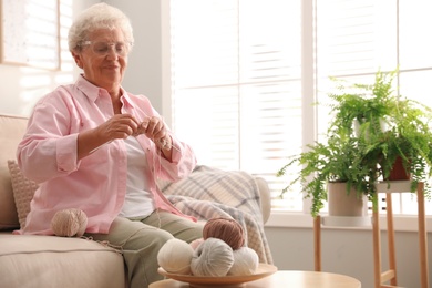 Photo of Elderly woman knitting at home. Creative hobby