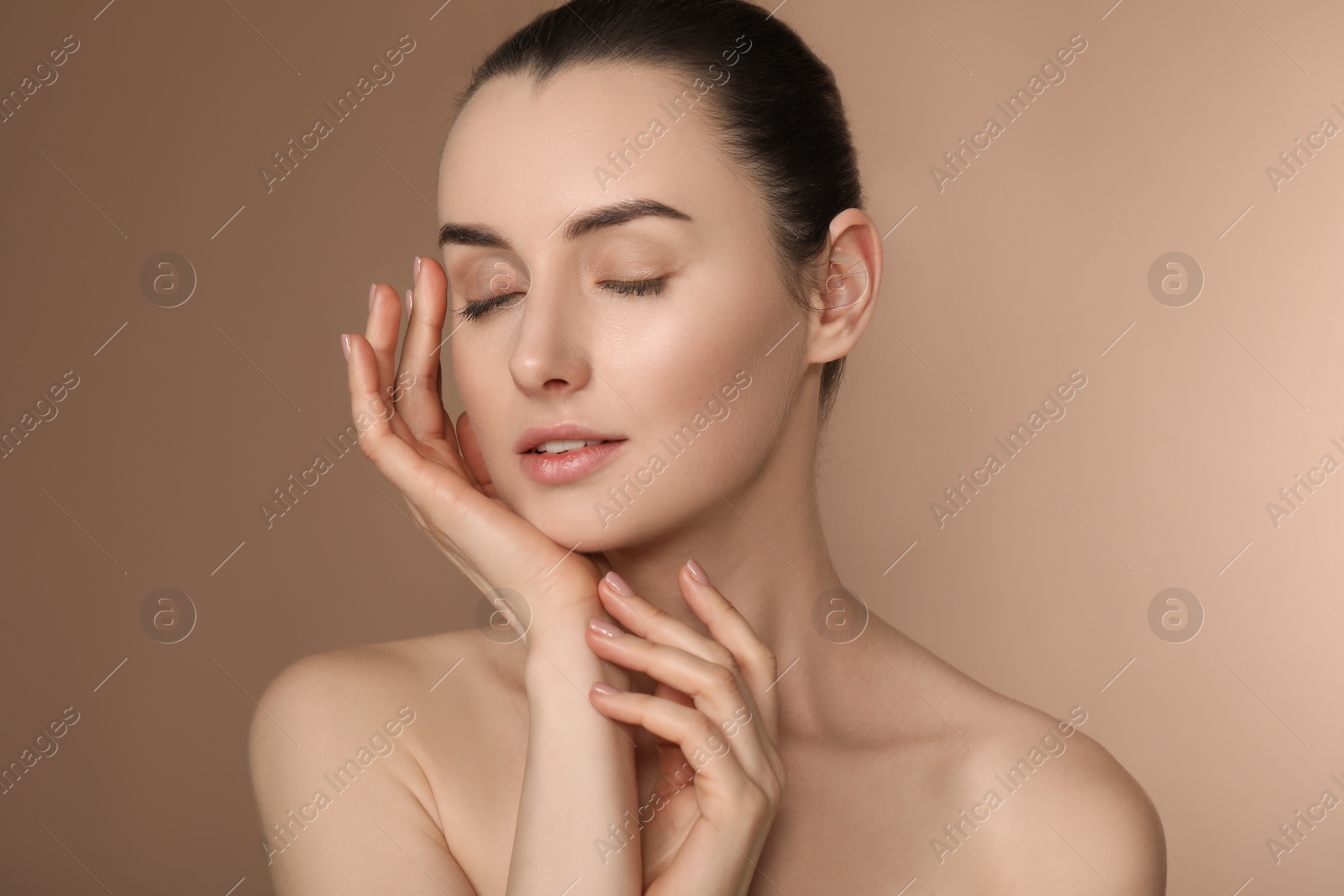 Photo of Portrait of beautiful young woman on light brown background