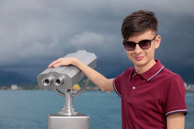 Photo of Teenage boy near mounted binoculars at sea