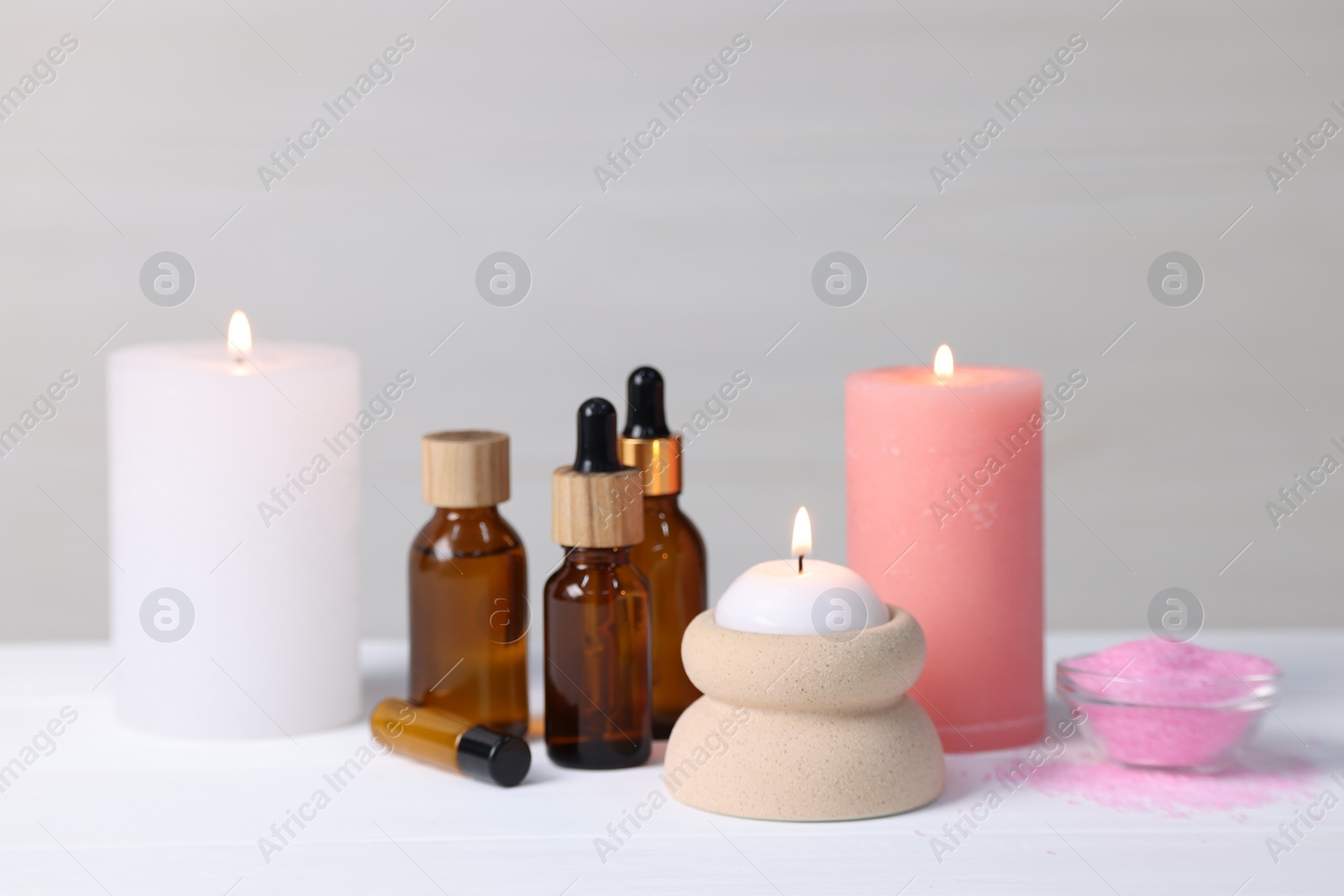 Photo of Different aromatherapy products and burning candles on white wooden table