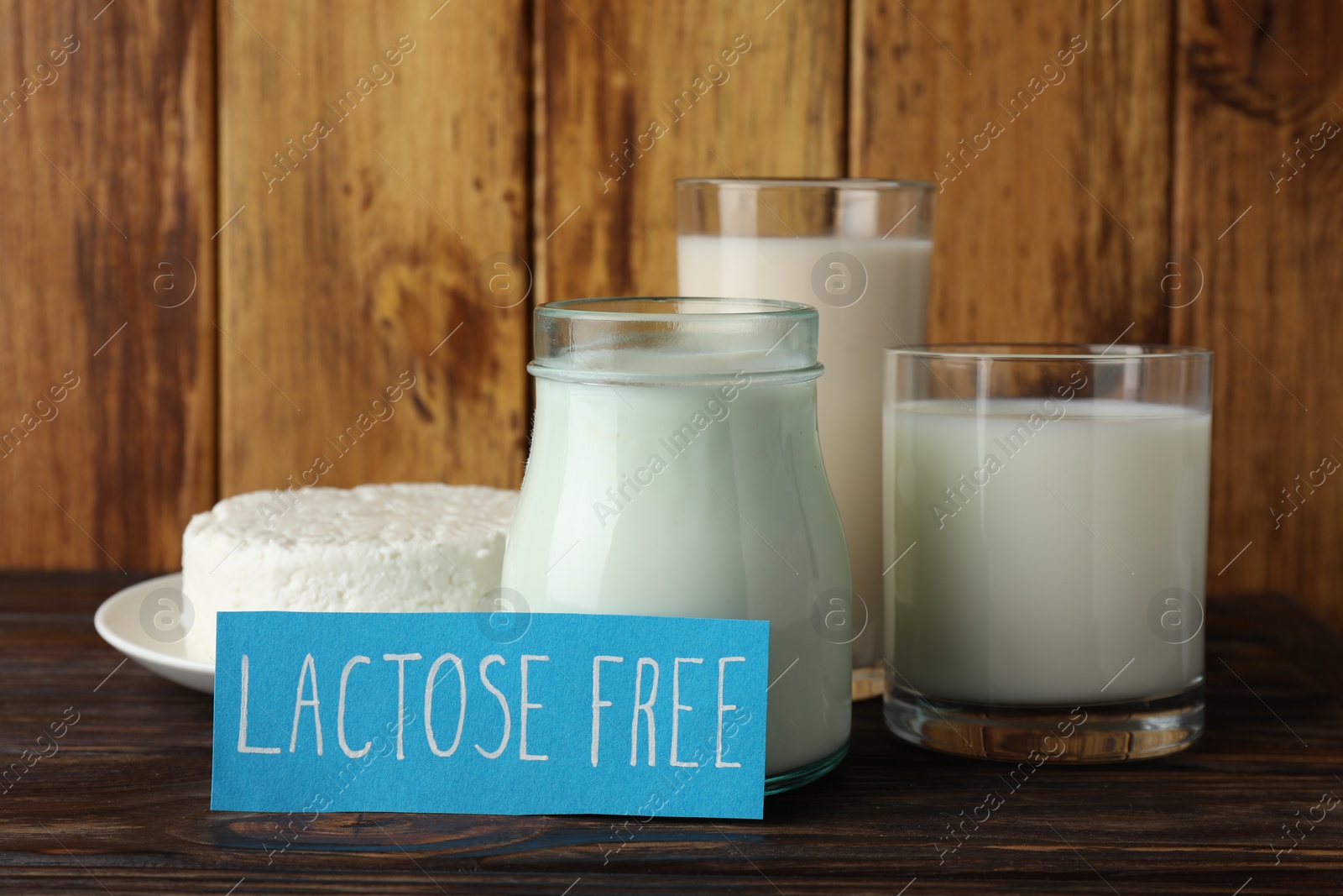 Photo of Card with phrase Lactose free and different fresh products on wooden table