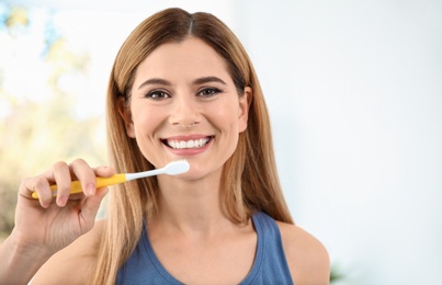 Portrait of woman with toothbrush on blurred background, space for text. Personal hygiene