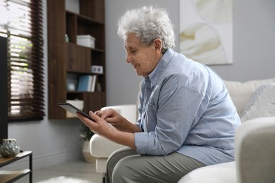 Photo of Elderly woman with poor posture using tablet in living room