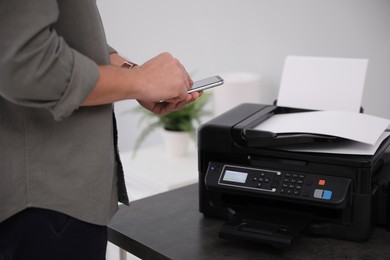 Photo of Employee using modern printer in office, closeup