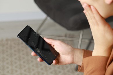 Woman holding damaged smartphone indoors, closeup. Device repairing