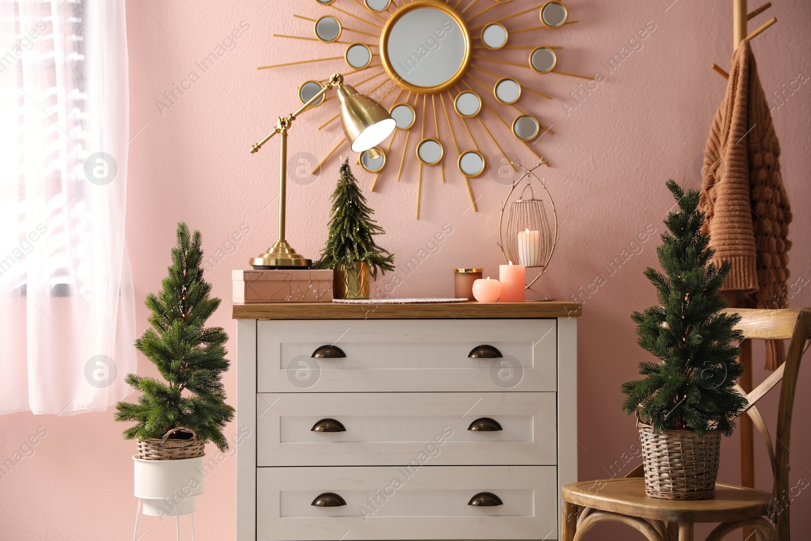 Photo of Stylish room interior with dresser and small fir trees