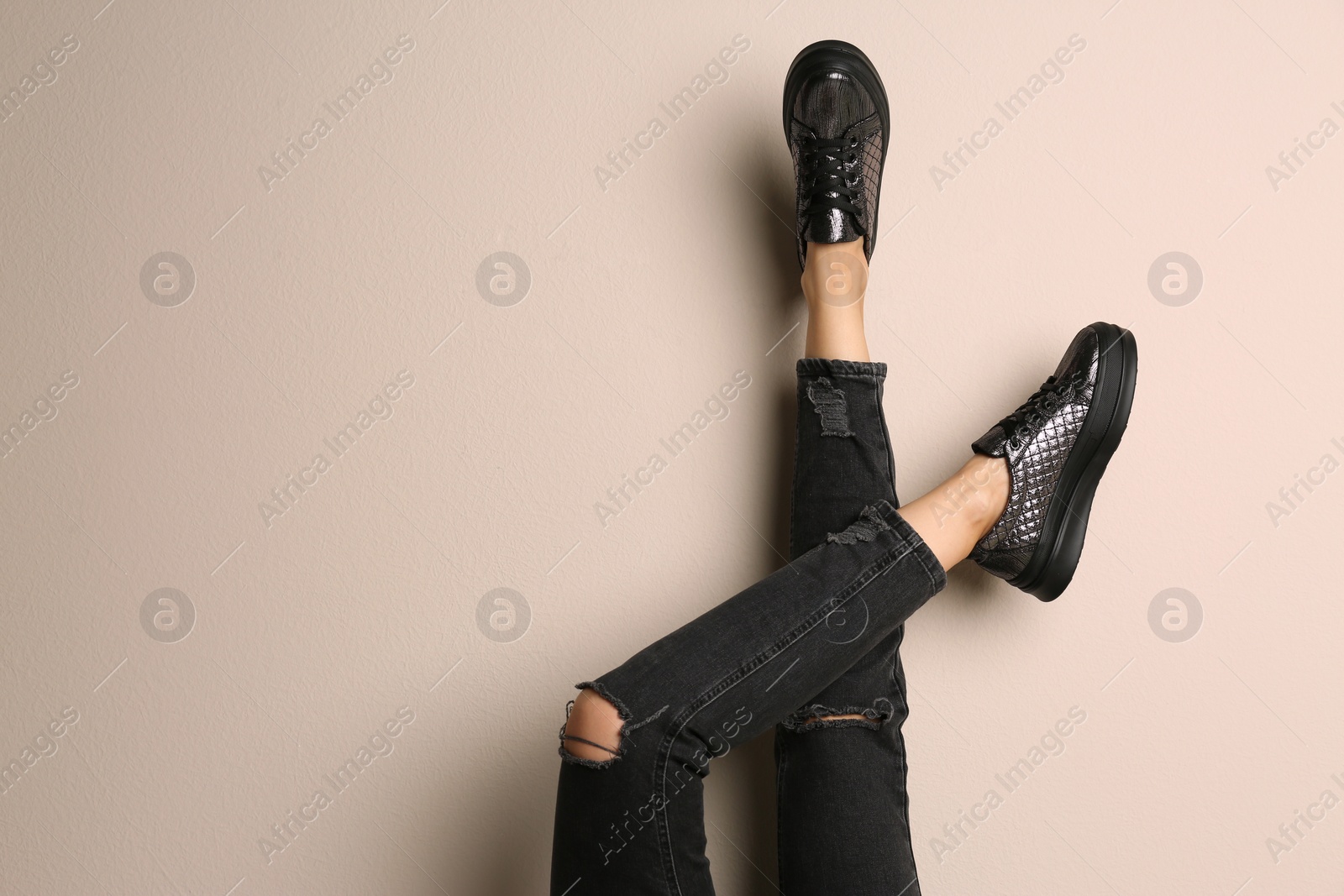 Photo of Woman wearing shoes on beige background, closeup. Space for text