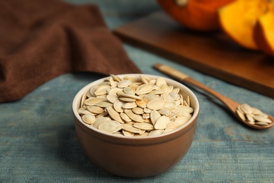 Photo of Bowl of raw pumpkin seeds on blue wooden table