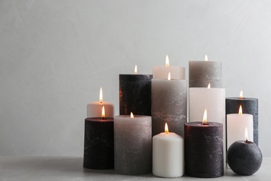 Set of burning candles on table against light background