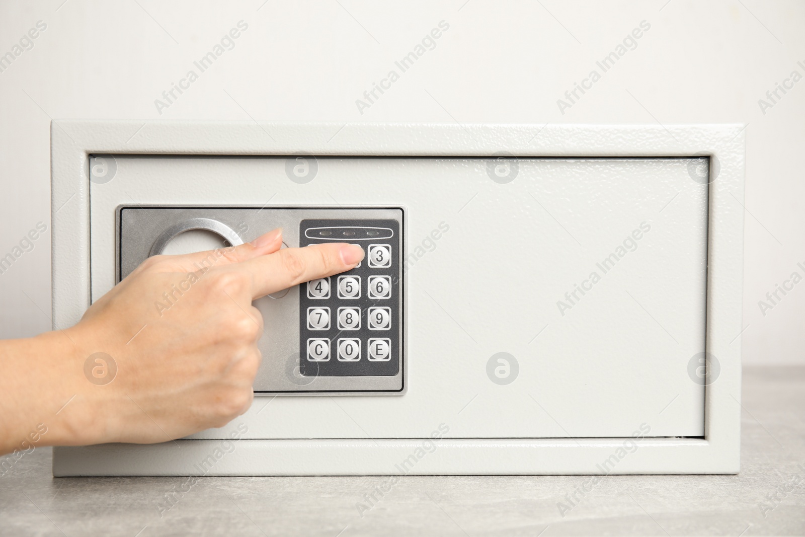 Photo of Woman opening steel safe with electronic lock, closeup