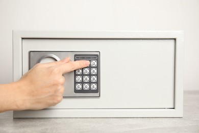 Woman opening steel safe with electronic lock, closeup
