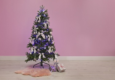 Beautiful Christmas tree near color wall indoors. Celebration time