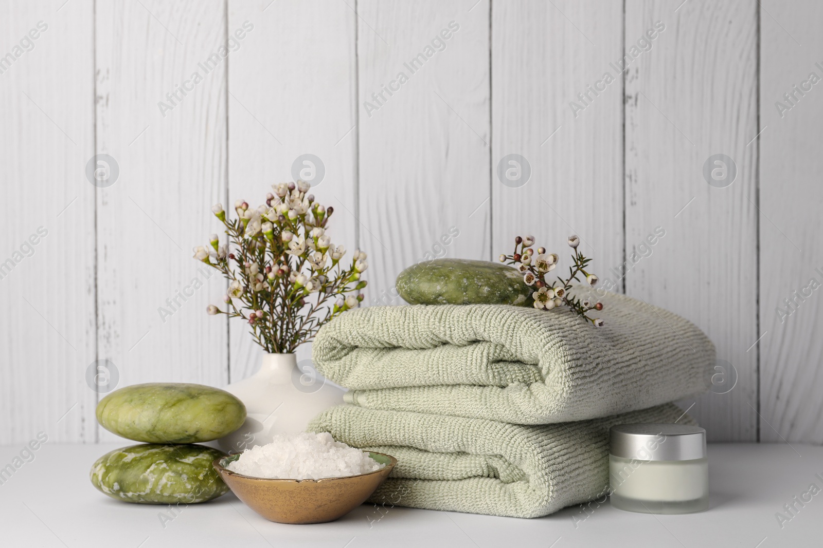 Photo of Composition with different spa products and flowers on white table against wooden background