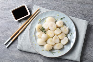 Raw scallops with lemon zest, rosemary and soy sauce on grey marble table, flat lay