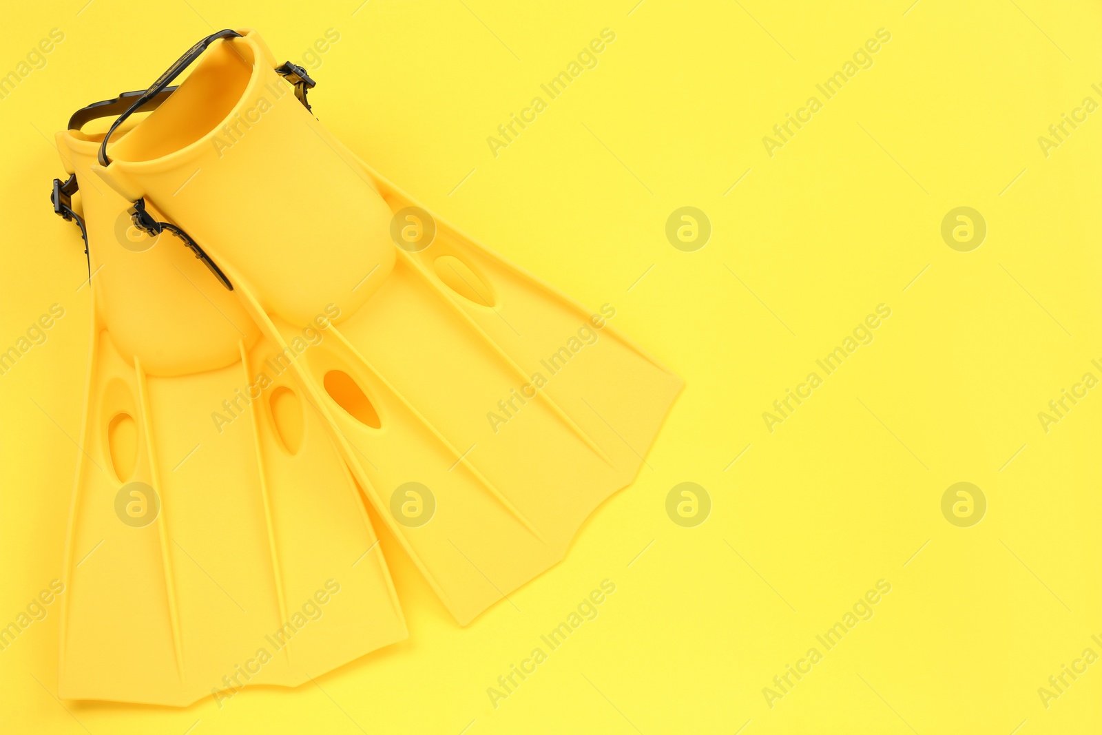 Photo of Pair of flippers on yellow background, flat lay. Space for text