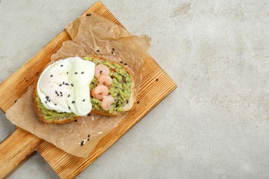 Photo of Delicious sandwich with guacamole, shrimps and fried egg on light grey table, top view. Space for text