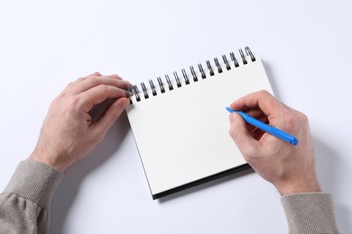 Man with pen and empty notepad on white background, top view