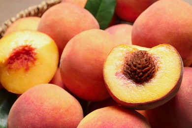 Photo of Cut and whole fresh ripe peaches in basket, closeup