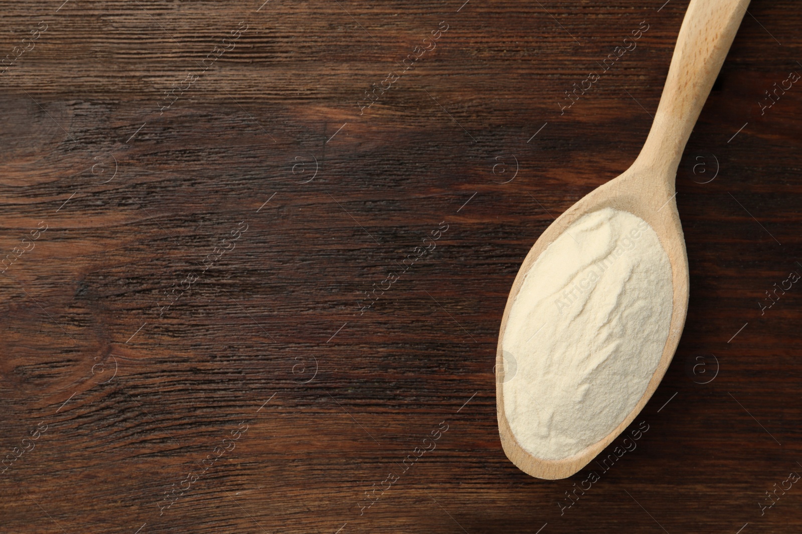 Photo of Spoon of agar-agar powder on wooden table, top view. Space for text