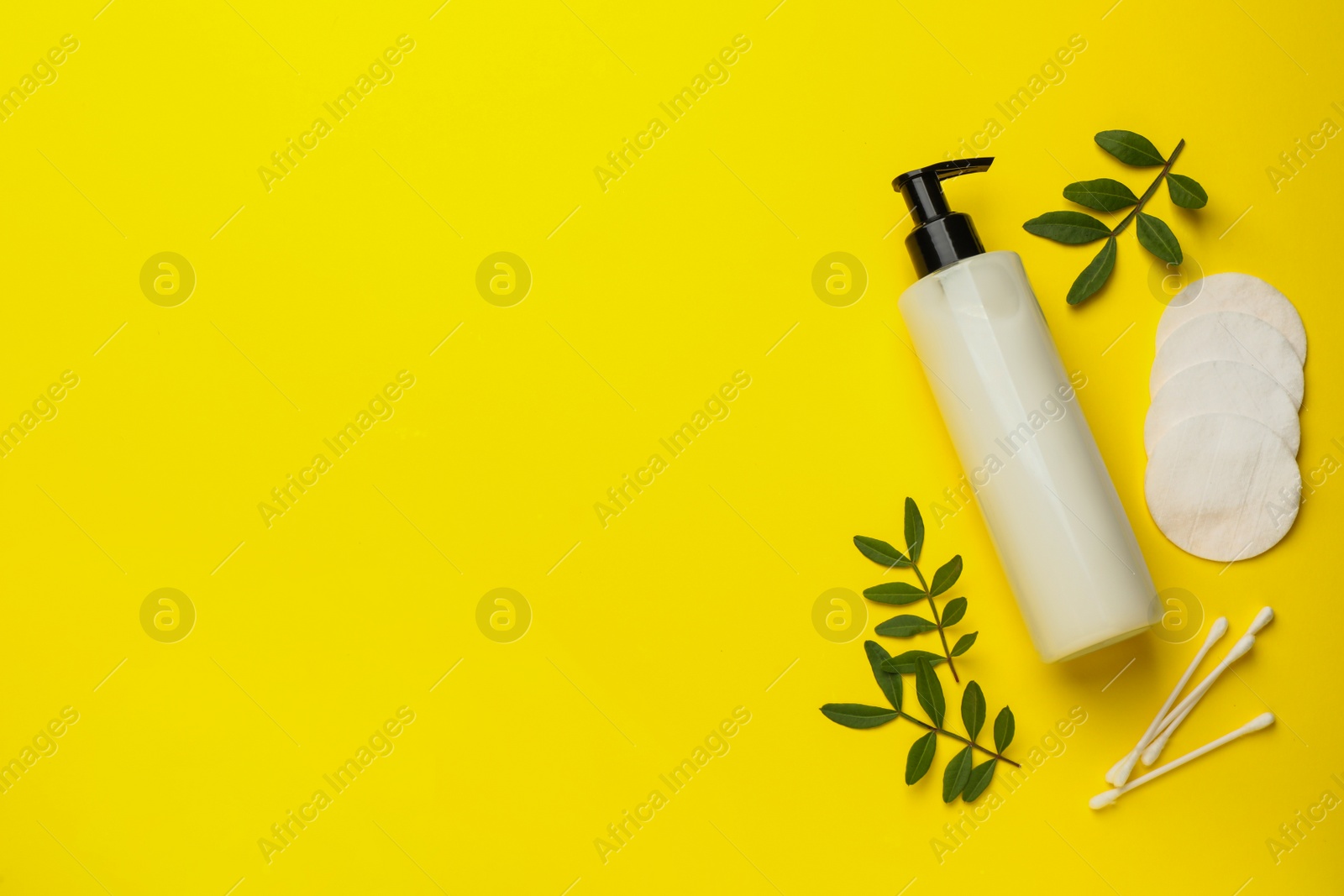 Photo of Cotton pads, swabs and makeup removal product on yellow background, flat lay. Space for text