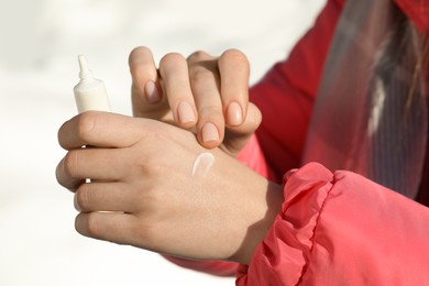 Photo of Woman applying moisturizing cream on hands in winter, closeup