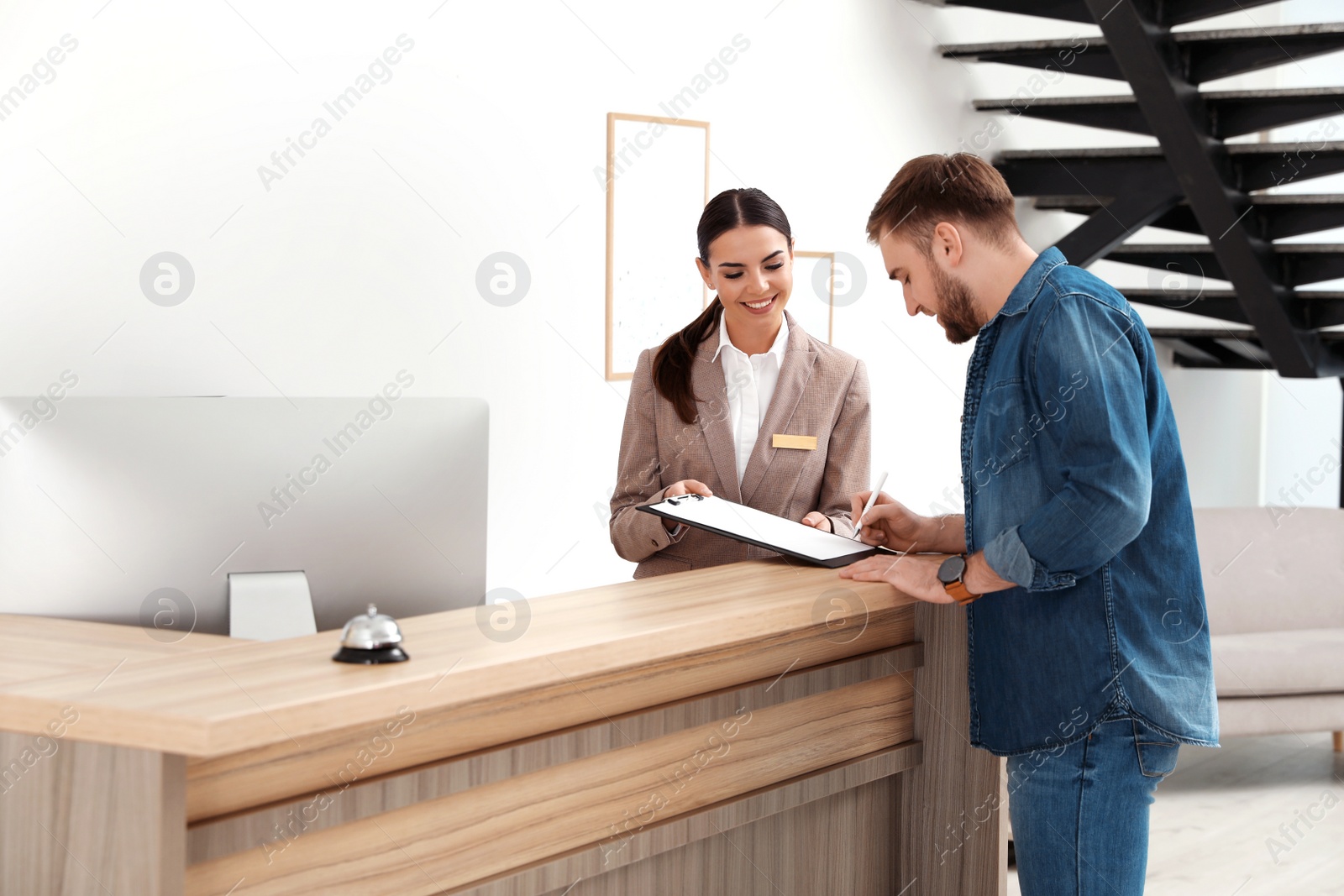 Photo of Professional receptionist working with client at desk in modern hotel