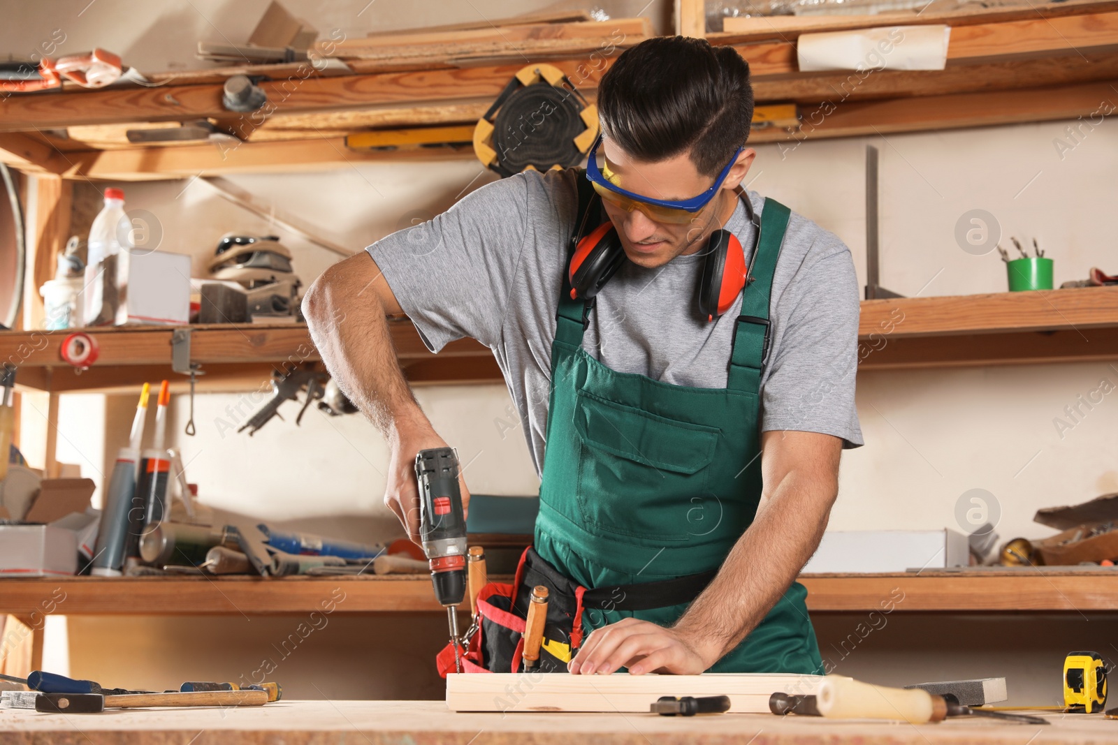 Photo of Professional carpenter twisting screw with drill at workbench