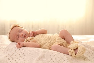 Photo of Adorable newborn baby sleeping on knitted plaid in room