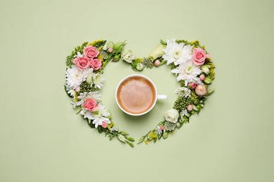 Photo of Beautiful heart shaped floral composition with cup of coffee on light green background, flat lay