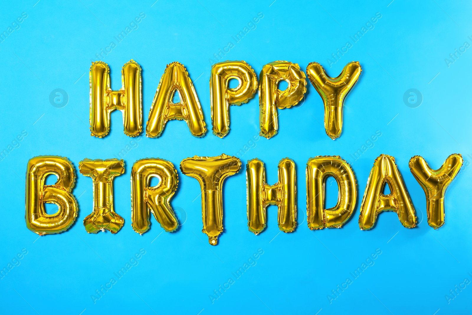 Photo of Phrase HAPPY BIRTHDAY made of foil balloon letters on light blue background