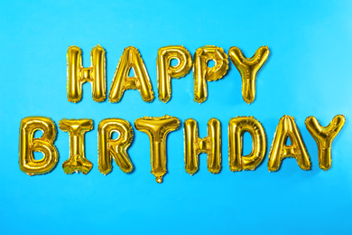 Photo of Phrase HAPPY BIRTHDAY made of foil balloon letters on light blue background