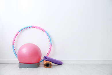 Different sports equipment near white wall in gym. Space for text