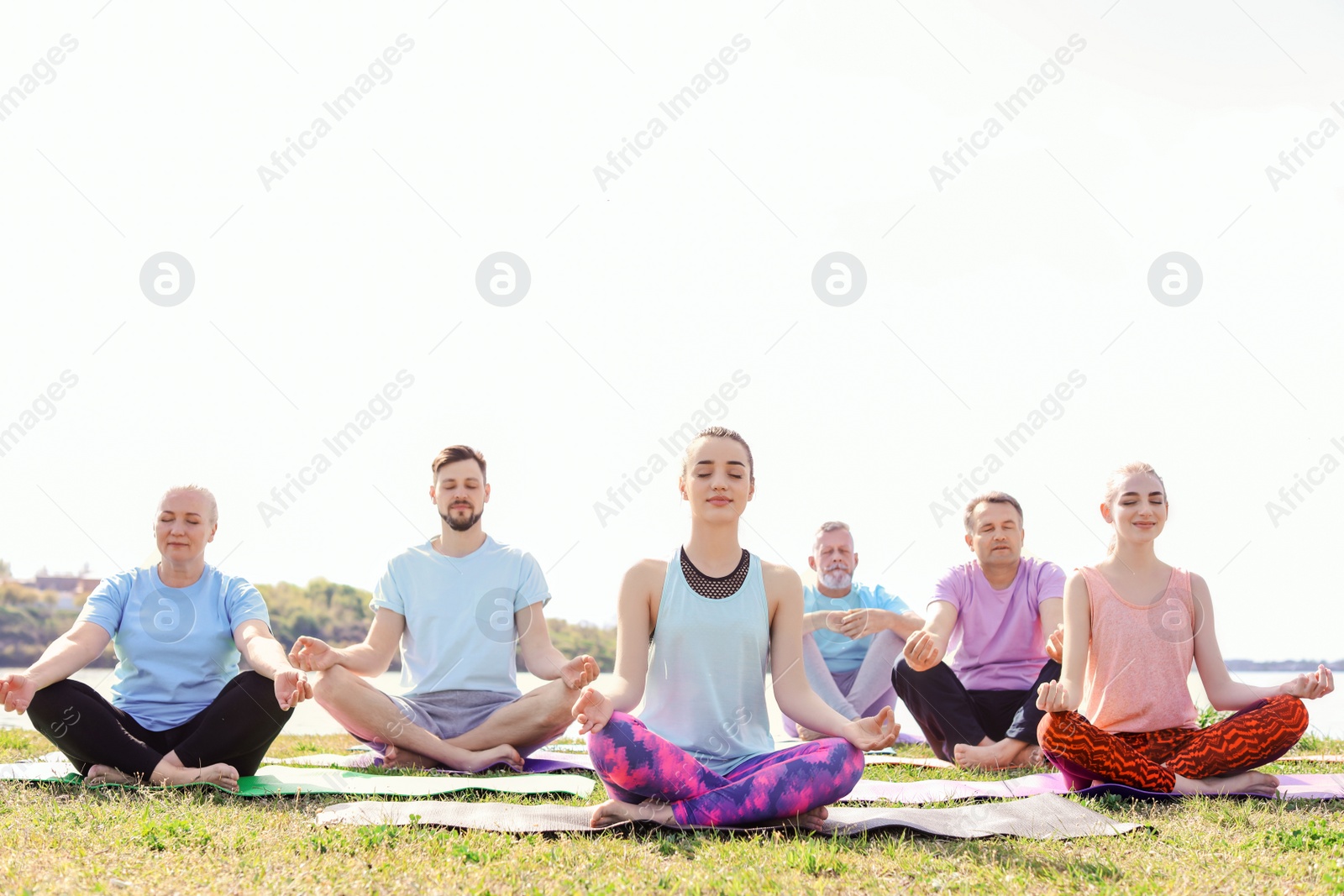 Photo of Group of people practicing yoga near river on sunny day