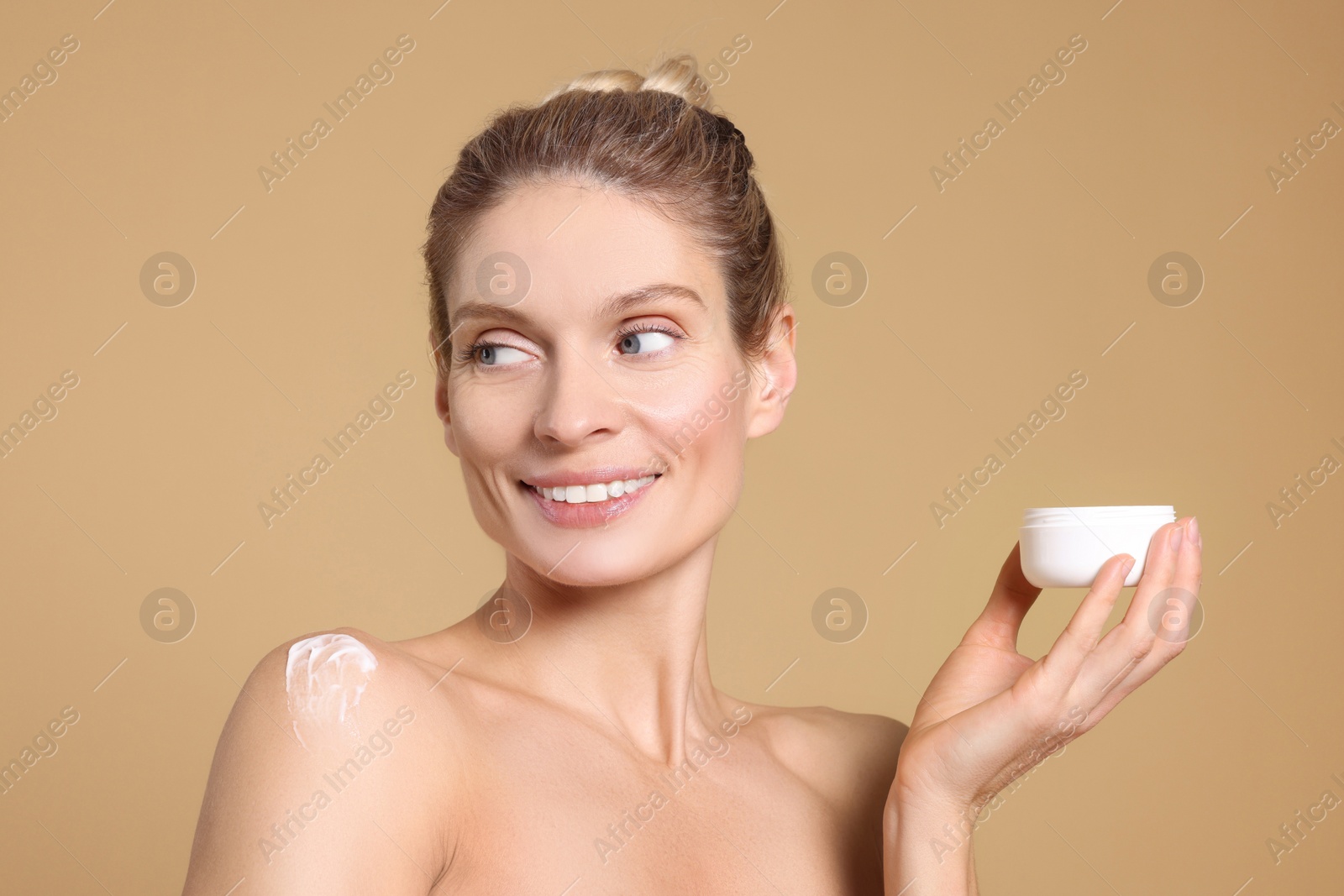 Photo of Woman with jar of body cream on beige background