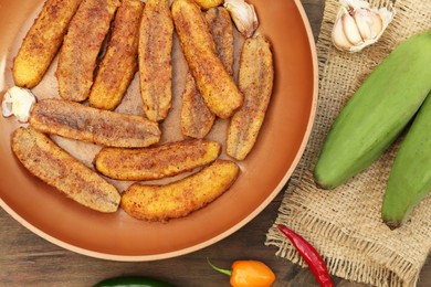 Photo of Delicious fried bananas, fresh fruits and different peppers on wooden table, flat lay