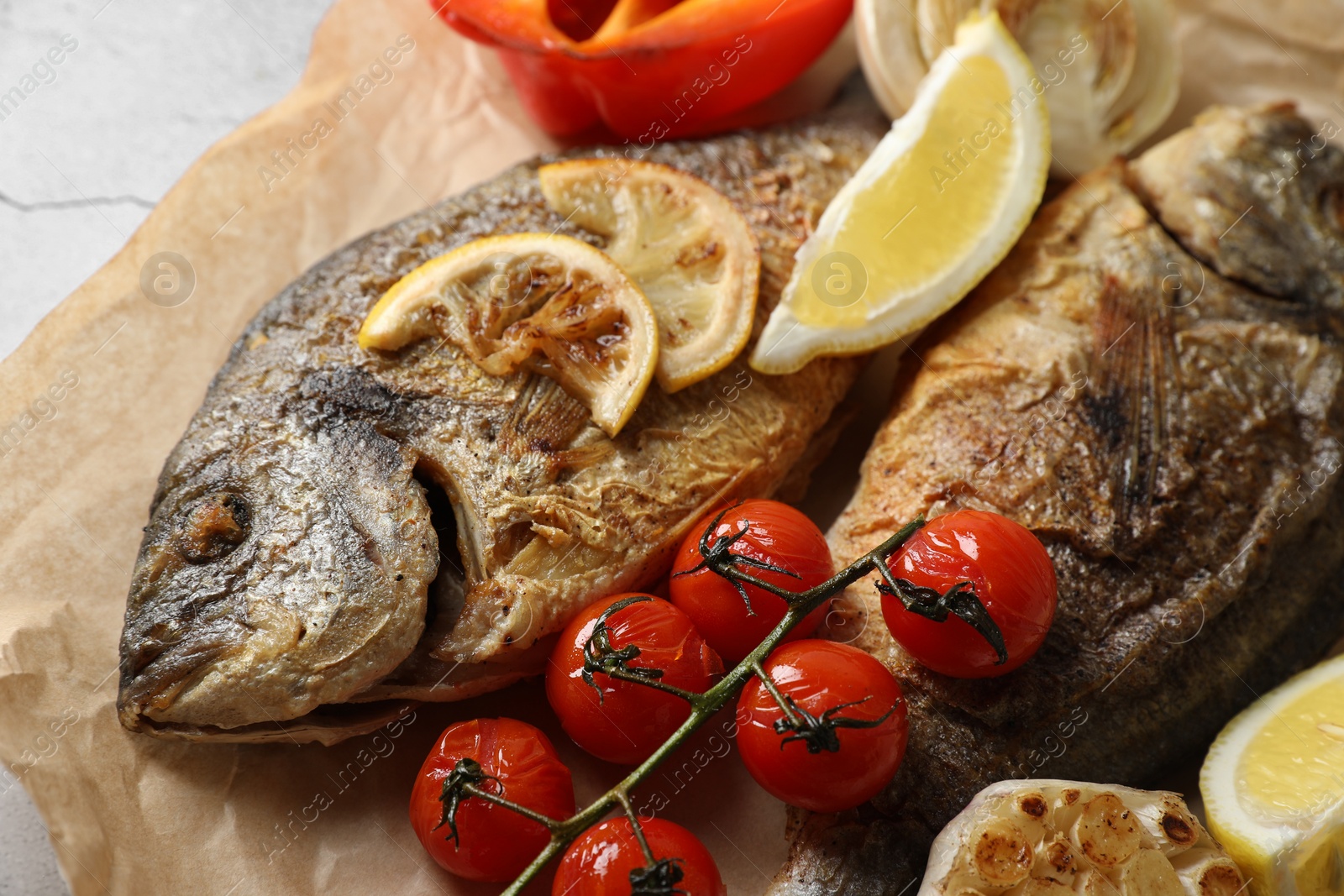 Photo of Delicious dorado fish with vegetables served on table, closeup