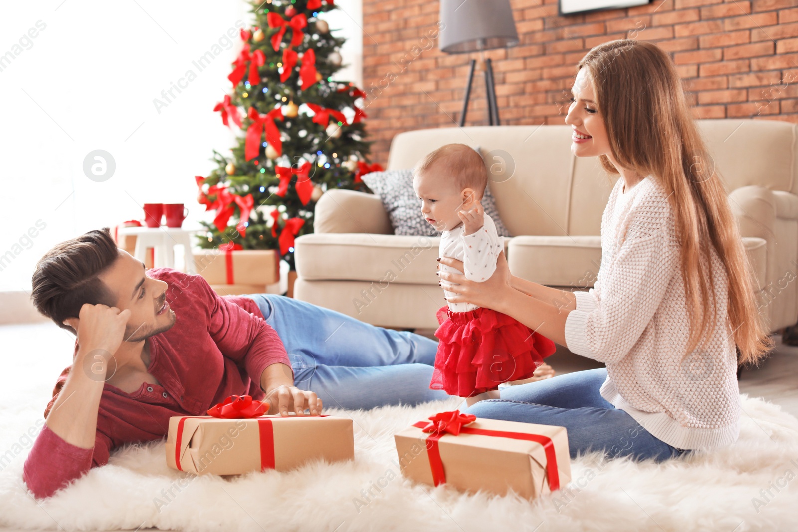 Photo of Happy couple with baby celebrating Christmas together at home