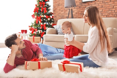 Happy couple with baby celebrating Christmas together at home