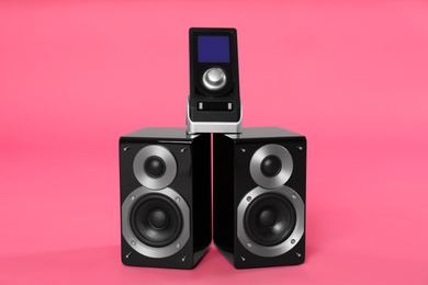 Photo of Modern powerful audio speakers with remote on pink background