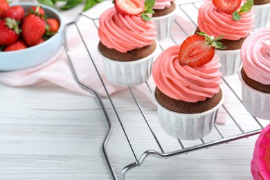 Photo of Delicious cupcakes with cream and strawberries on white wooden table