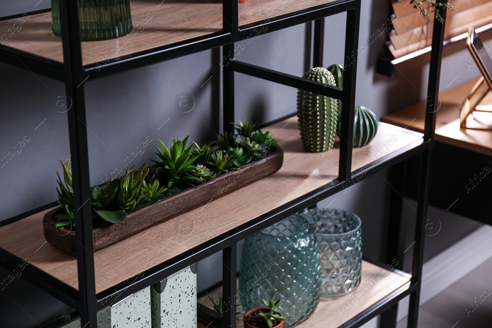 Photo of Shelving with different decor and houseplants near gray wall. Interior design