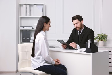 Human resources manager reading applicant's resume during job interview in office
