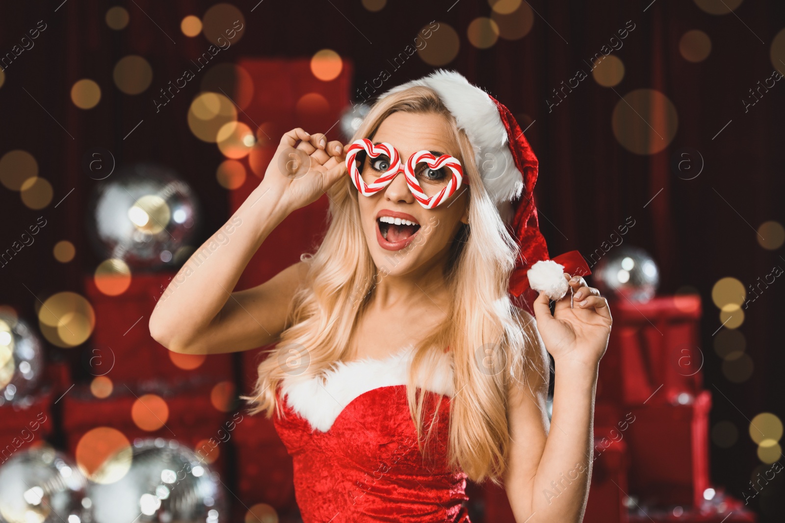 Image of Beautiful young woman in Christmas costume against blurred lights