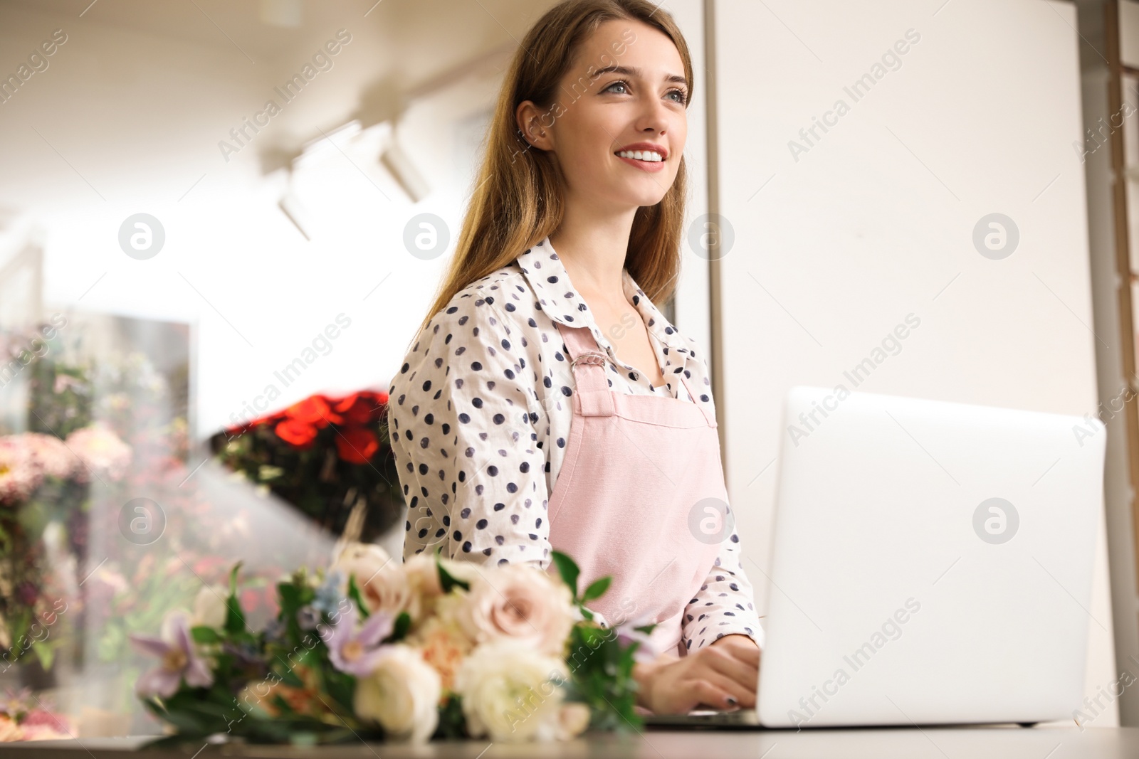 Photo of Professional female florist using laptop at workplace